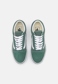 Paire de baskets basses vertes et blanches avec des lacets blancs, vues de dessus sur un fond clair.