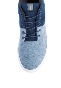 Niebieskie filcowe buty z gradientowym wzorem, z ciemnoniebieskimi akcentami i sznurowadłami oraz białą gumową podeszwą. Gładka tekstura i luźny styl.