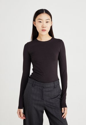 Zwart langemouwen top gemaakt van rekbare stof, met een ronde hals en een slim-fit ontwerp, gecombineerd met grijze streepjesbroek.