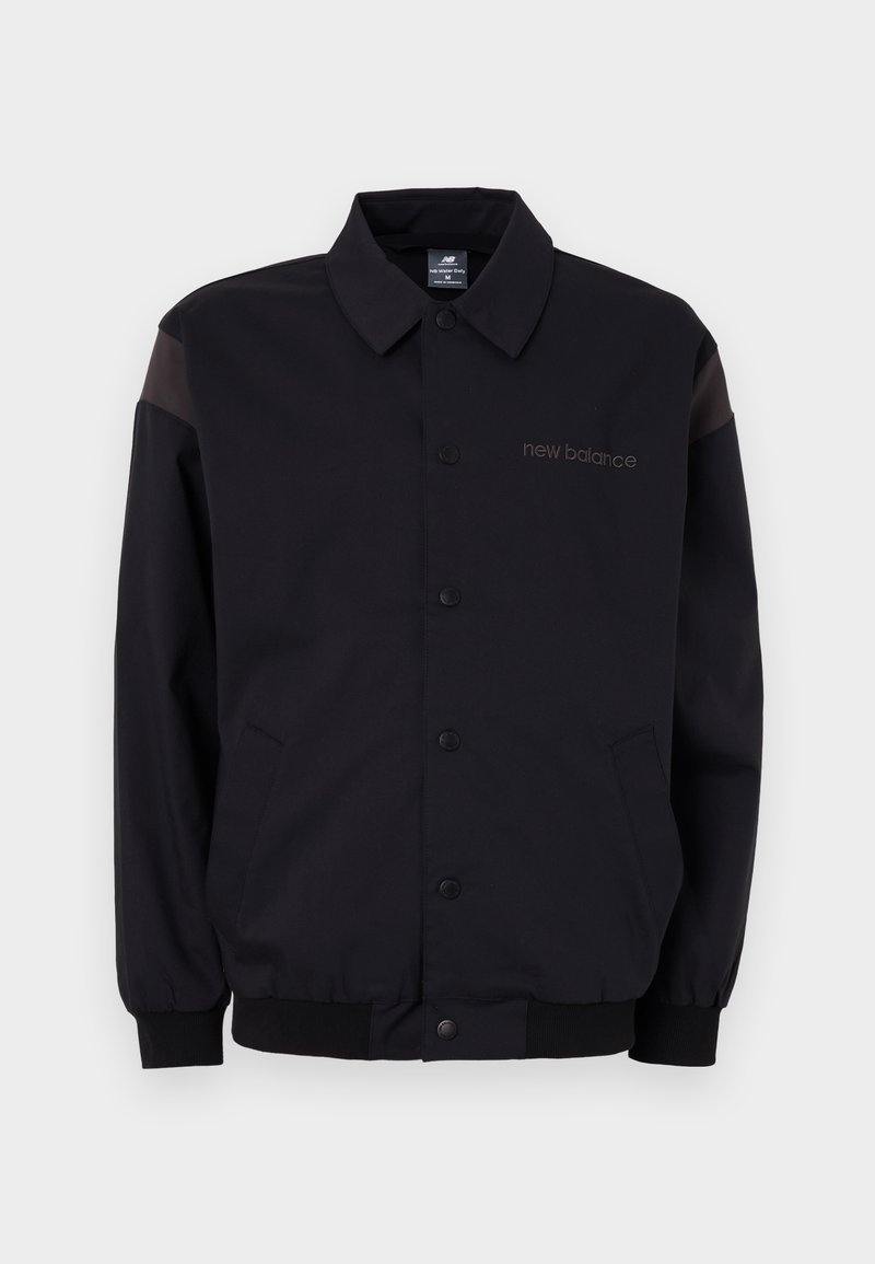 Chaqueta negra con cierre de botones en el frente, puños y cuello acanalados. Presenta paneles en los hombros de contraste y un logo en el pecho. Textura suave.
