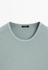 Light blue crew-neck t-shirt made from soft cotton, featuring a smooth texture and subtle ribbed pattern around the neckline and sleeves.