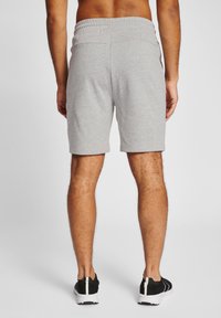 Grå bomullsshorts med elastisk midja, som slutar ovanför knäet. Har en mjuk textur och en neutral design, i kombination med svarta träningsskor.