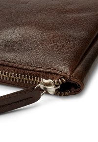 Brun läderclutch med texturerad yta, utrustad med ett silverfärgat blixtlås och ett handledsband. Märkbara sömmar längs kanterna.