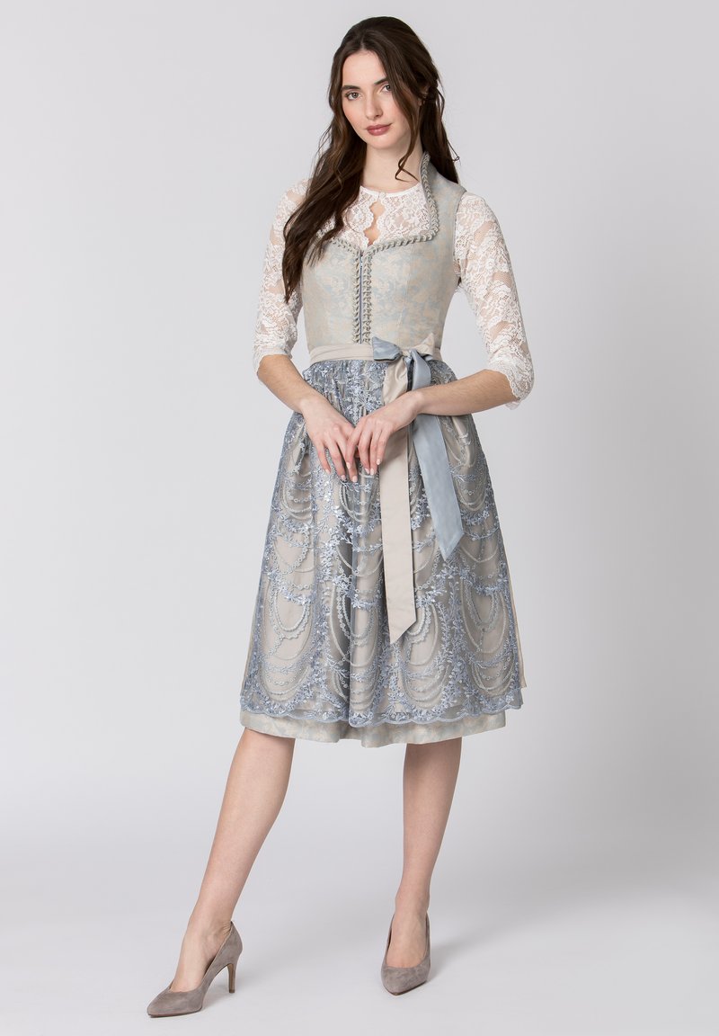 Light blue dirndl dress with intricate silver embroidery, lace sleeves, and a satin bow at the waist, paired with gray heels.