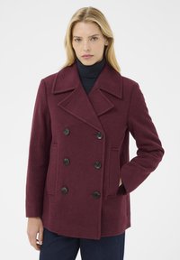 Burgundska volnena peacoat jakna z dvojnim zapenjanjem, črnimi gumbi in dvema sprednjima žepoma. Zarezan ovratnik in sproščen kroj.