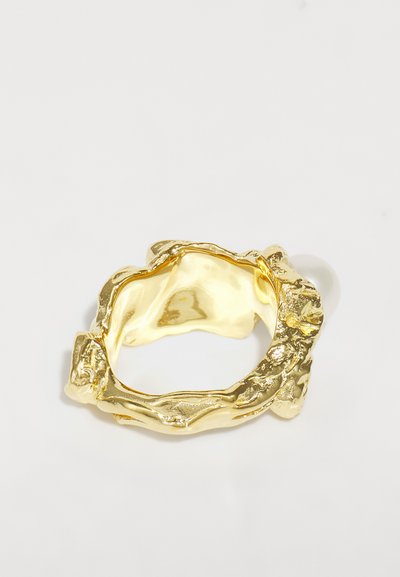 Gold ring with an irregular, textured design, featuring a thick band and visible grooves on the surface. Smooth interior finish.