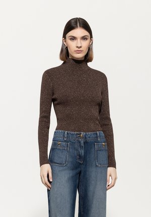 Braunes, langärmliges Rollkragensweatshirt mit einem subtilen Glanz, kombiniert mit weiten blauen Denim-Jeans mit Fronttaschen und Knopfakzenten.