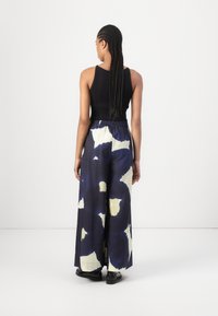 Black ribbed tank top paired with wide-leg pants featuring a blue and cream abstract pattern, with an elastic waistband and smooth texture.
