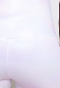 White leggings with a reflective, shiny texture. Smooth fabric shows subtle color variations in light, with a high waistband design.