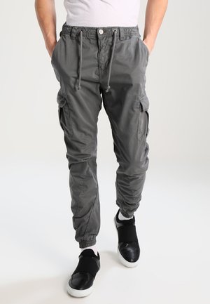 Pantalons cargo légers en gris foncé, dotés d'une taille à cordon de serrage, de poches latérales et de poignets élastiques. Associés à des chaussures à enfiler noires.
