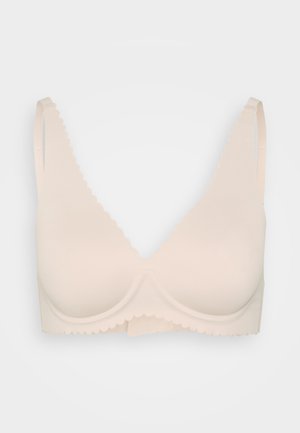 Lys beige bh med glatte kopper, scalloped kanter, justerbare stropper og et sømløst design. Laget av myk, elastisk stoff.