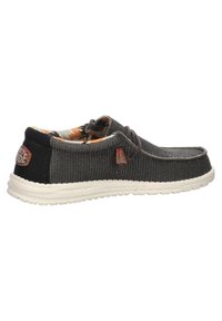 Scarpe slip-on in tela di colore grigio scuro, con una parte superiore testurizzata, suola in gomma bianca e una fodera floreale colorata visibile all'apertura.
