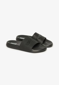 Zwarte rubberen teenslippers hebben twee brede banden met reliëfbranding aan de bovenkant. De zolen zijn plat en hebben een structuur voor grip.
