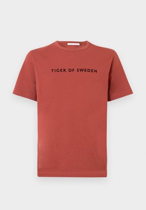 Camiseta de algodón de manga corta en color rojo óxido, con cuello redondo y el texto "TIGER OF SWEDEN" en negro en el pecho.
