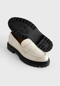 Mocassini in pelle verniciata beige con suola in gomma nera, caratterizzati da un design classico, stile slip-on e un sottile dettaglio cucito.