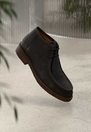 Brune læder ankelstøvler med rund tå, diskrete syninger og snørebåndsdesign. Letvægts sål med tekstureret finish.