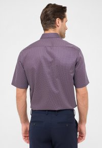 Korte mouwen, paarse blouse met een geometrisch patroon, met een rechte kraag en gladde stof, gedragen met donkerblauwe broek.