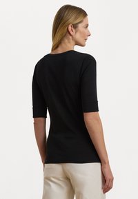 Zwarte aangesloten T-shirt met halve mouwen en opgerolde manchetten, gemaakt van een gladde stof. Heeft een eenvoudige ronde halslijn en geen zichtbare patronen.