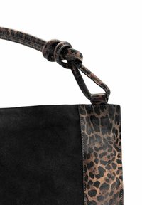 Sac à main en daim noir avec des finitions en imprimé léopard et un détail de bandoulière nouée en imprimé léopard sur fond blanc.