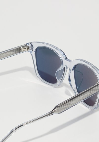 Translucent light blue sunglasses with gray lenses; curved cat-eye shape; silver-accented temples featuring engraved "Giorgio Armani" logo.