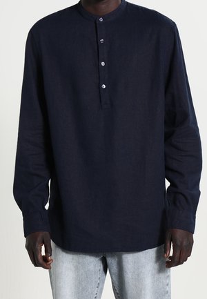 Camicia a maniche lunghe blu navy con colletto rotondo, apertura a tre bottoni e vestibilità leggermente rilassata, realizzata in tessuto testurizzato.