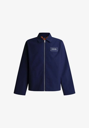 Marineblaue Zip-Up-Jacke mit Kragen, langen Ärmeln und einem Red Bull Racing Logo-Patch auf der linken Brust.