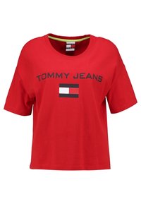 Camiseta de algodón roja con mangas cortas, que presenta el texto "TOMMY JEANS" y un gráfico de bandera en negro, blanco y rojo en la parte frontal.