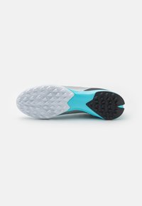 Suela de zapato con una base blanca, goma negra texturizada en el talón y un acento en aqua, con un diseño curvado para mayor agarre y estabilidad.