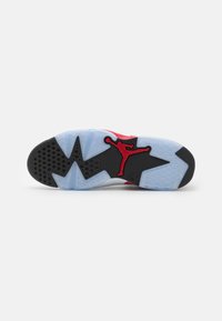 Suela de zapatilla negra y roja con una sección de goma azul transparente que presenta un patrón texturizado y un acento de logo. Elementos de diseño angulares destacados.