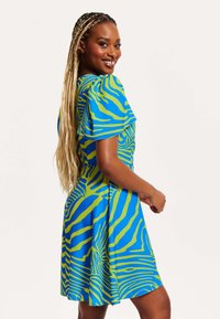 Short-sleeve dress featuring a blue fabric with green abstract stripes, flared design, and a smooth texture.