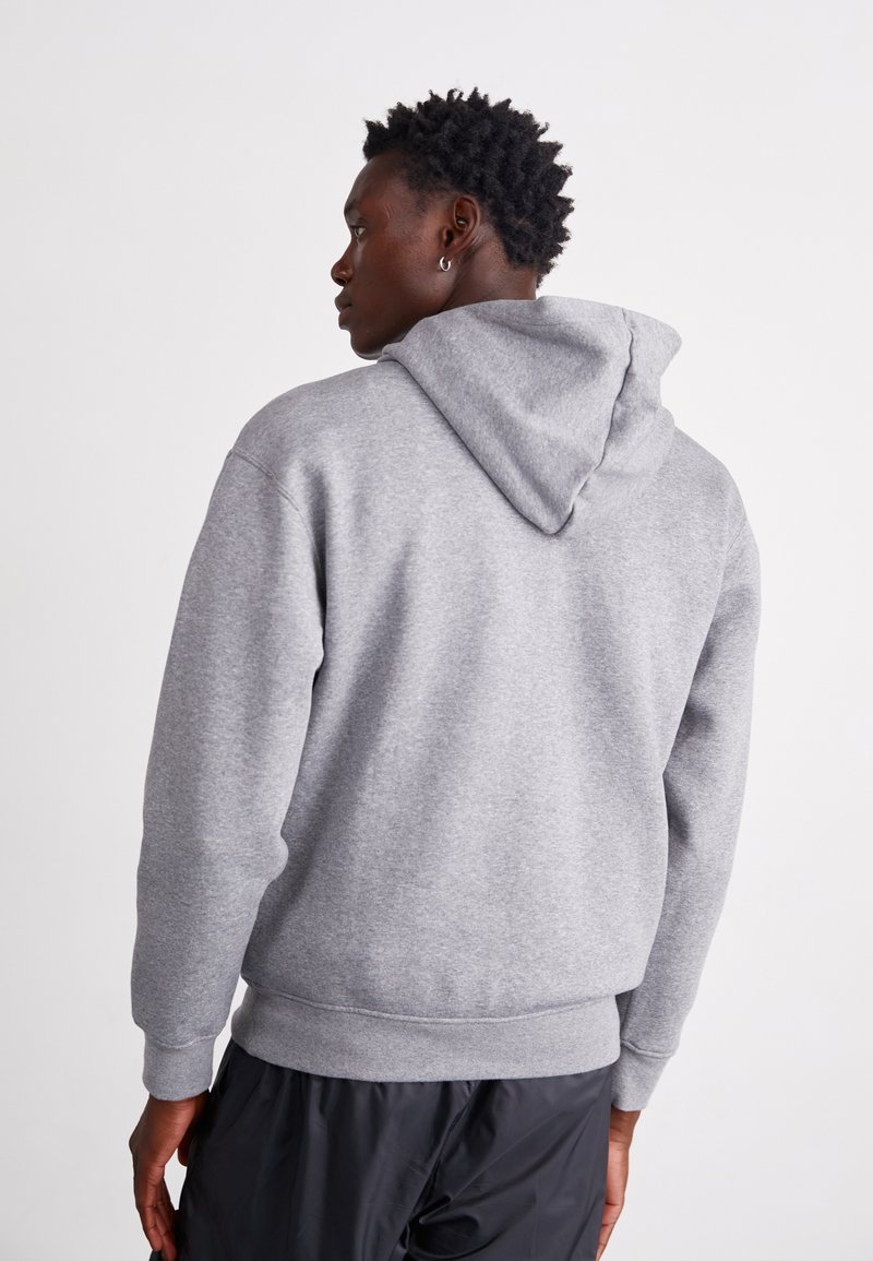 Grauer Hoodie aus weichem Material mit einer Kordelzugkapuze, gerippten Bündchen und Saum. Sieht leicht oversized aus mit einer glatten Textur und ohne Muster.