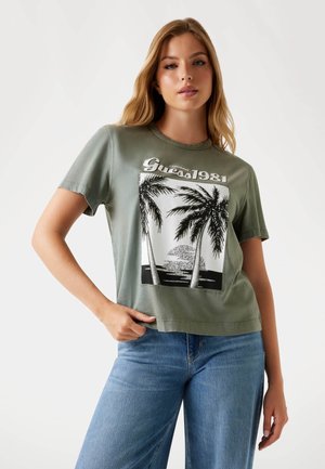 T-shirt in cotone verde oliva con stampa grafica raffigurante palme e un tramonto. Maniche corte e vestibilità relax. Stile casual.