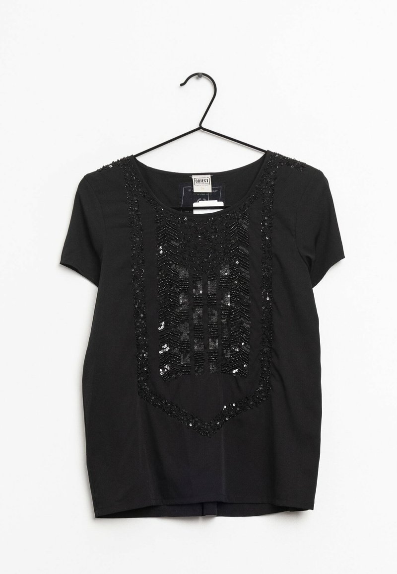 Haut noir à manches courtes avec un col arrondi, orné de sequins noirs décoratifs formant un motif géométrique sur le devant. Suspendu à un crochet noir.