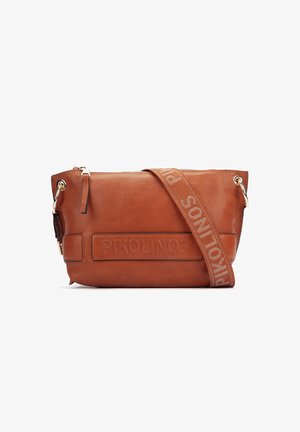 Bolso cruzado de cuero marrón con el logo en relieve "PIKOLINOS" y una correa ancha de tela con el nombre de la marca a juego en letras grandes.