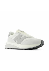 Vita och grå sneakers med en texturerad yta, som har en vadderad sula, snörning och en framträdande "N"-logotyp på sidan.