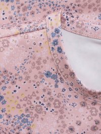 Blommönstrad rosa tyg med blå, gula och bruna accenter. Har rund halsringning och en mjuk, elastisk textur.