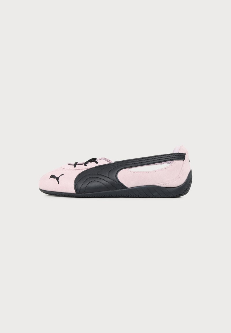 Ballerine Puma rose clair et noire avec logo noir sur la pointe et semelle texturée, vue de profil latéral sur fond uni.