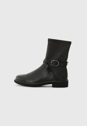 Bottines noires avec une finition en cuir lisse, un haut élastique et une sangle décorative avec une boucle en argent. Forme de bout rectangulaire et semelle plate.