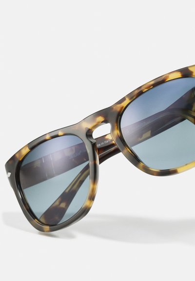 Ochelari de soare cu lentile polarizate de culoare tortoise brown, având un ușor gradient. Rama este groasă și de formă pătrată, cu un pod tăiat.