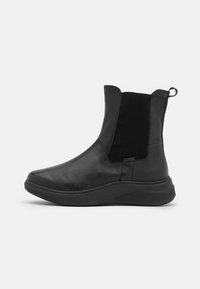 Botas negras de tobillo hechas de cuero suave con paneles laterales elásticos, punta redondeada y una suela de goma gruesa para mayor tracción.