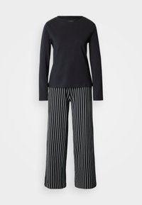 Haut noir à manches longues avec encolure ronde, associé à un pantalon large à rayures verticales noires et blanches. Matière en coton, design décontracté.