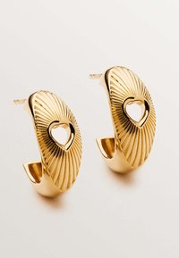 Pendientes de aro en tono dorado con textura estriada y un corte en forma de corazón en el centro, con un acabado suave y pulido.