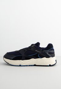 Navy blue athletic sneaker with mesh and suede materials, chunky white midsole, blue accents, and a textured sole for grip.