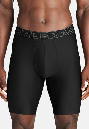 Schwarze athletische Boxershorts mit glatter Textur, ausgestattet mit einem Logo-Gummibund und einem engen Design, das bis zur Mitte des Oberschenkels reicht.
