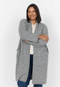 Cardigan gris clair, fabriqué en matériau tricot doux, présente une coupe ample, des manches longues, de profondes poches avant et un design à ouverture frontale.