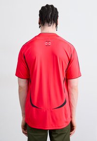 Red short-sleeve athletic shirt with a round neck, featuring black accents and a logo on the upper back. Smooth, lightweight fabric.