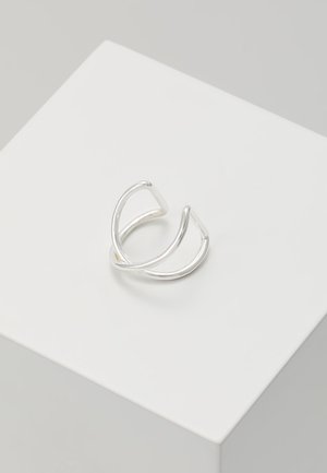Boucle d'oreille minimaliste en argent en forme de créole ouverte avec un double anneau, placée sur une plateforme carrée blanche sur un fond gris clair.