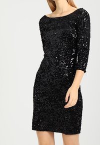 Svart paljettklänning med trekvartslånga ärmar och båtformad halsringning. Sitter tajt runt kroppen, har en slät textur och en knä-lång klippning.