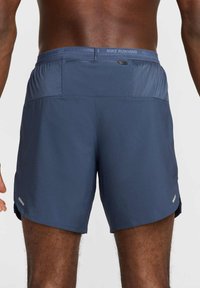 Pantalones cortos de running Nike de color azul marino, fabricados con material ligero, que presentan un panel de malla en la parte trasera, una cintura elástica y detalles reflectantes.