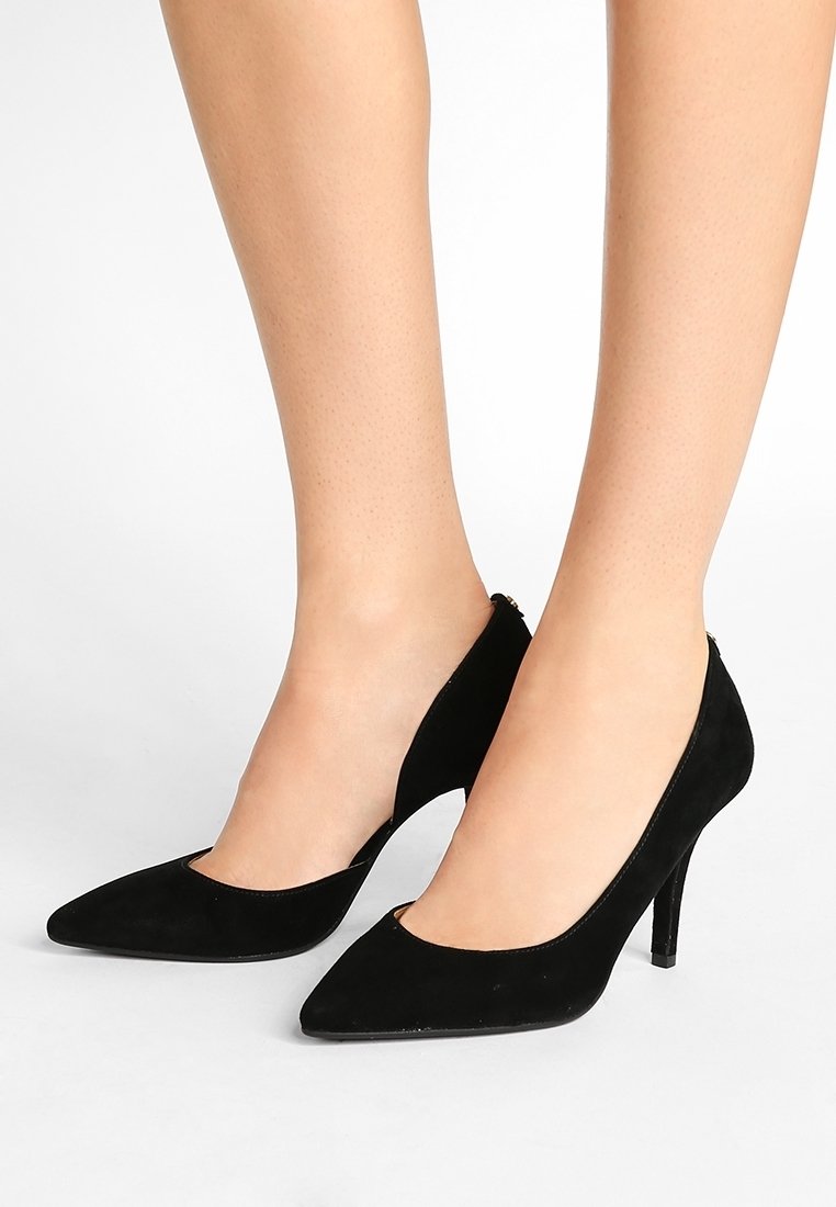 Escarpins en daim noir avec un bout pointu et des côtés ajourés. Les talons sont fins, d'environ 7,5 centimètres de hauteur, et présentent une texture lisse.